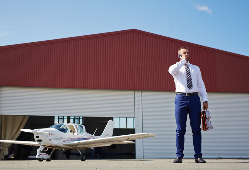Pilot on the phone next to his airplane