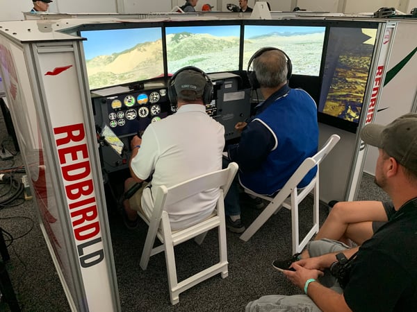 A pilot and flight instructor flying a flight simulator scenario in the Pilot Proficiency Center at AirVenture