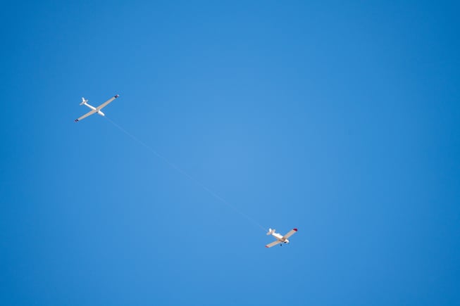 A glider tow pilot tows a glider through clear skies