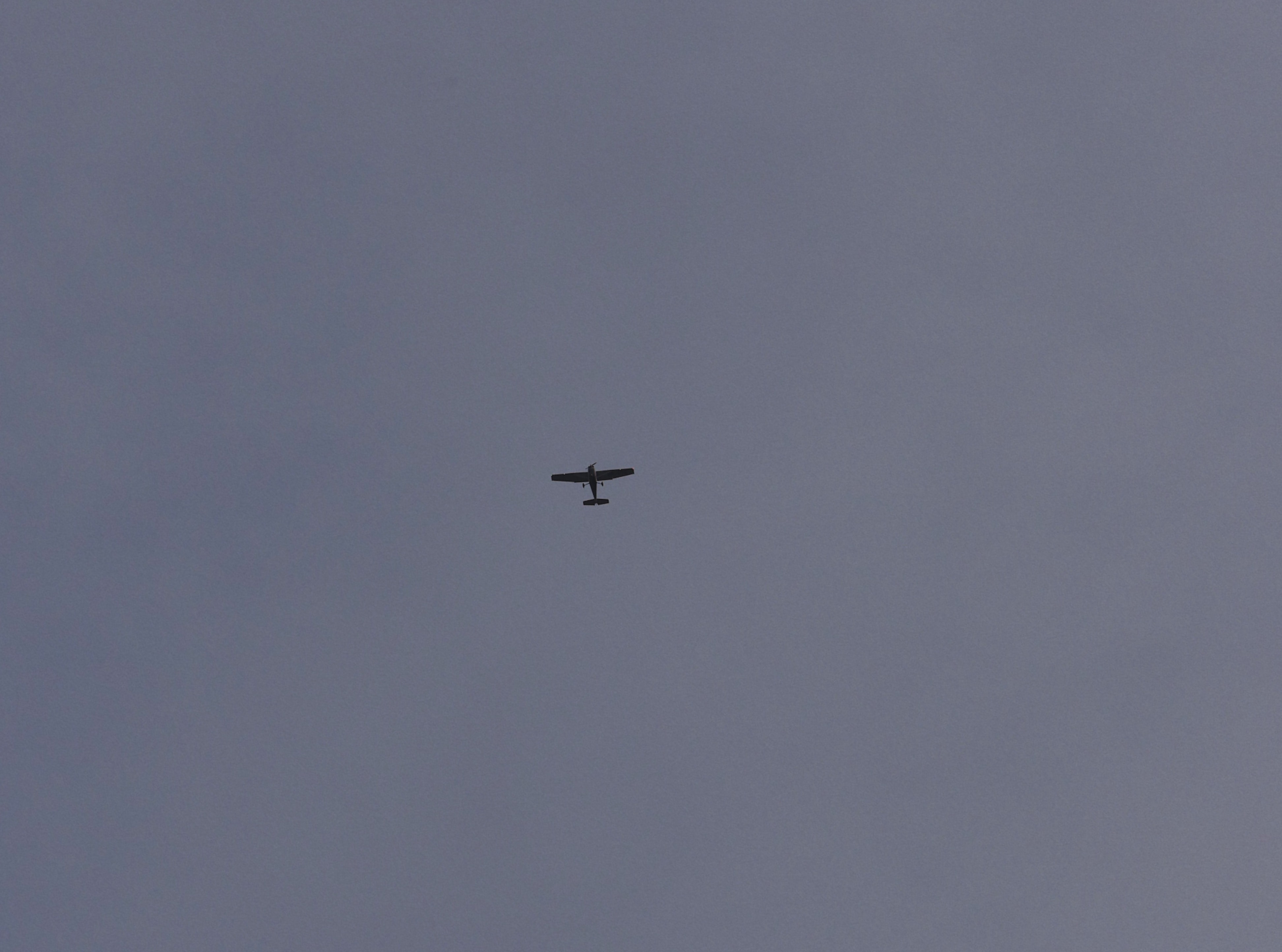 Airplane flying across a grey sky
