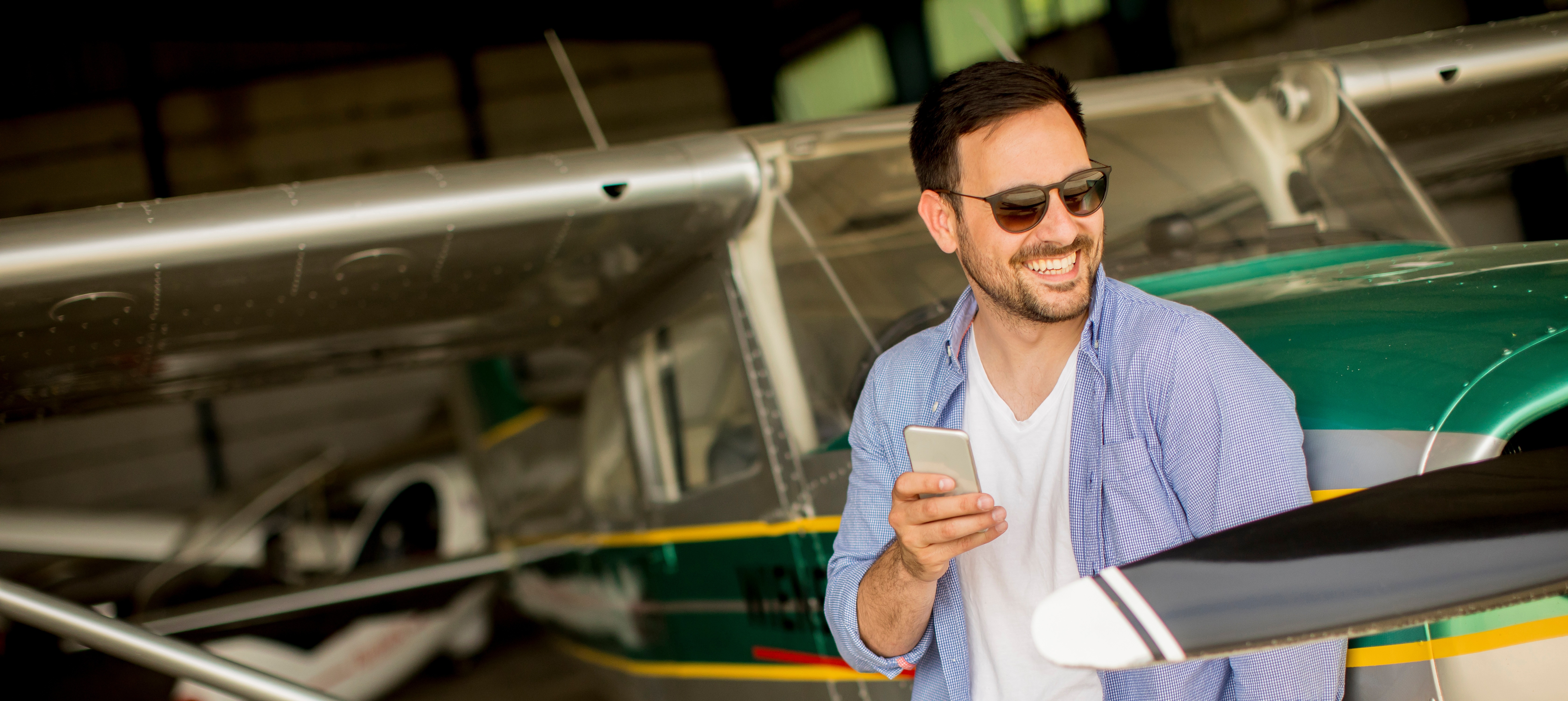 Pilot next to his airplane getting a brief on his smartphone