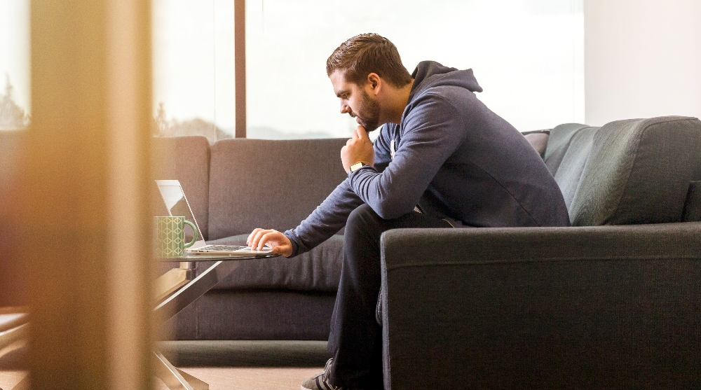 Man sitting on a couch working on his laptop