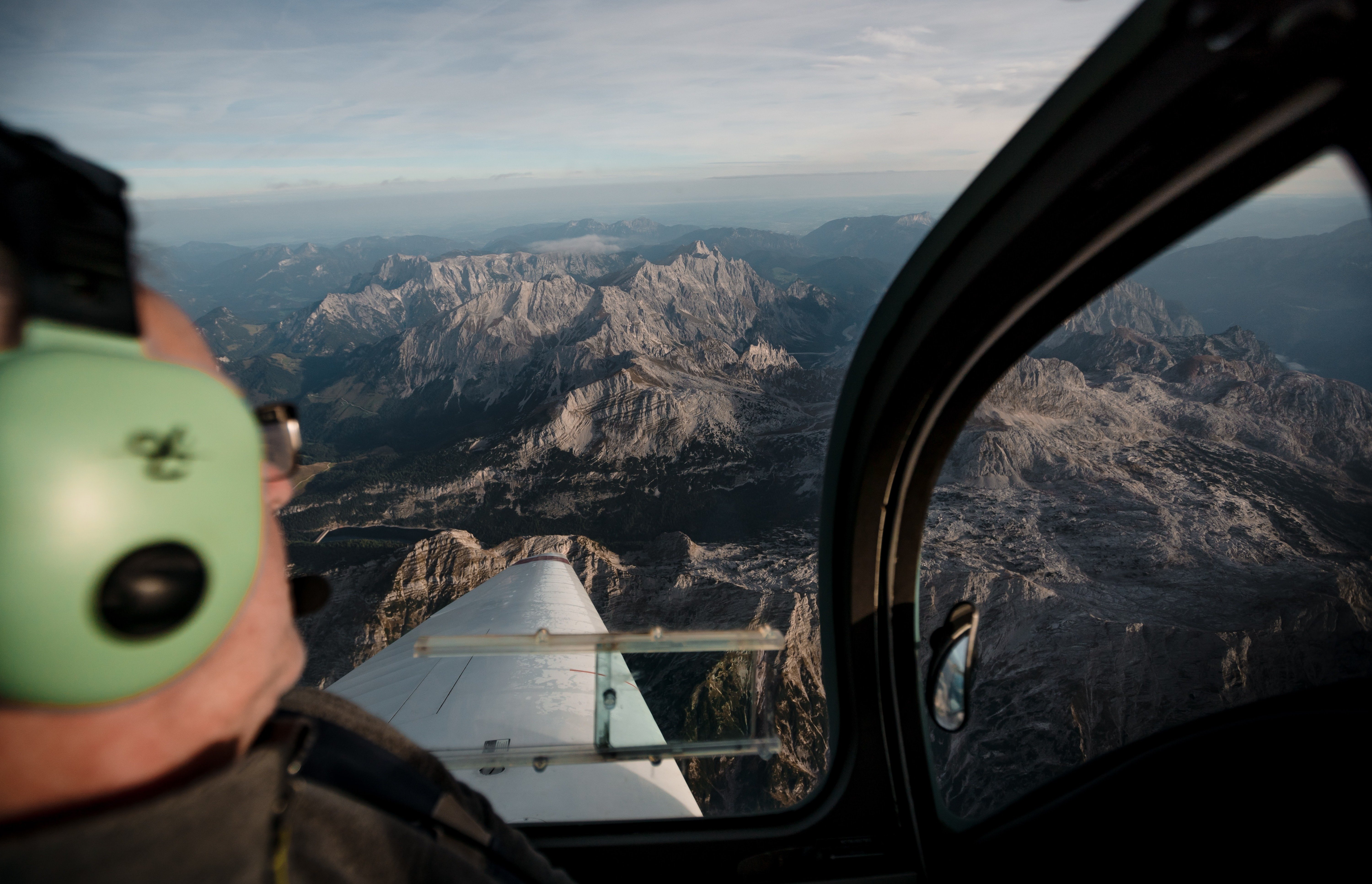 Pilot looking over the mountains from the left seat of his aircraft