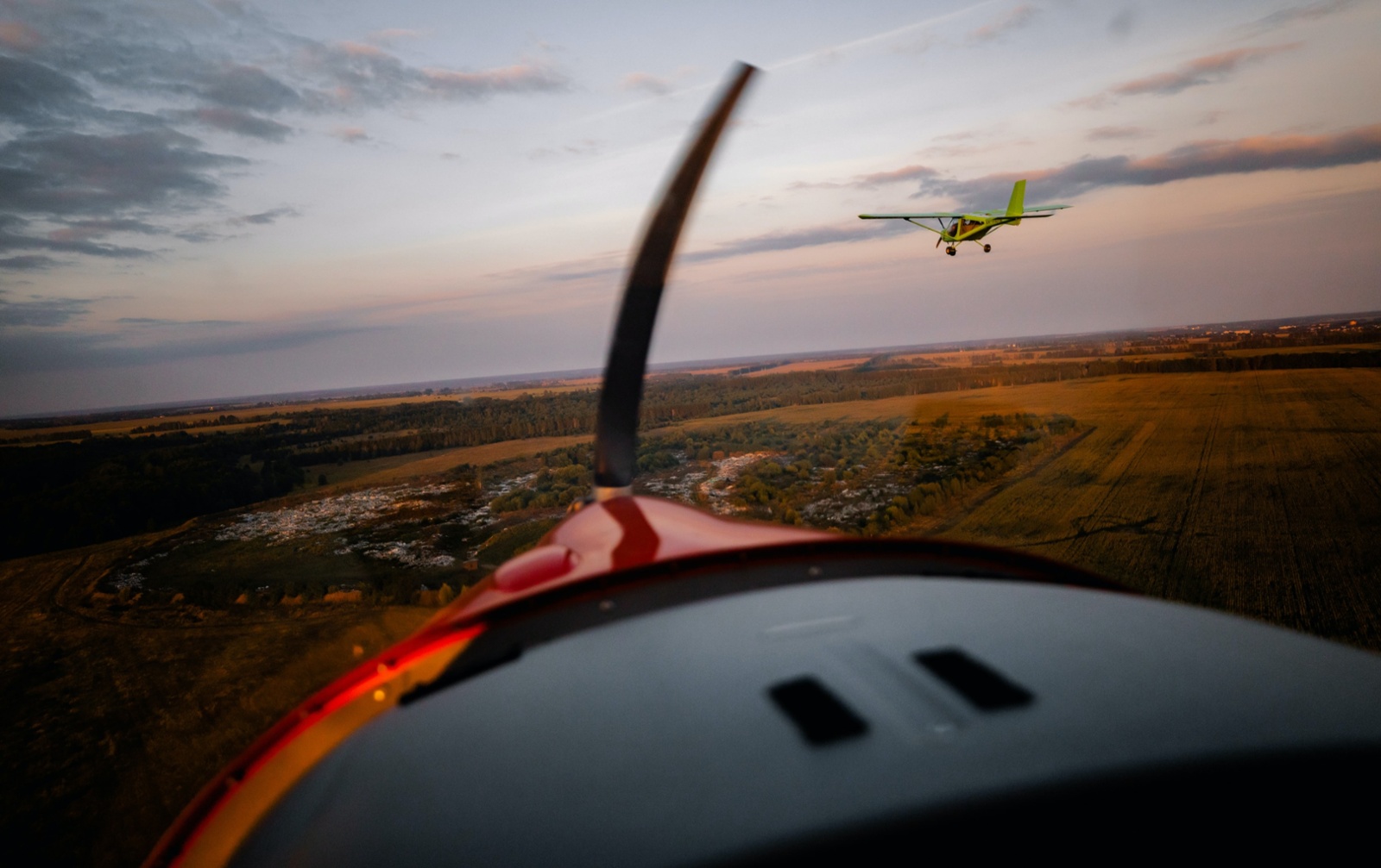 Two general aviation airplanes flying over a rural landscape